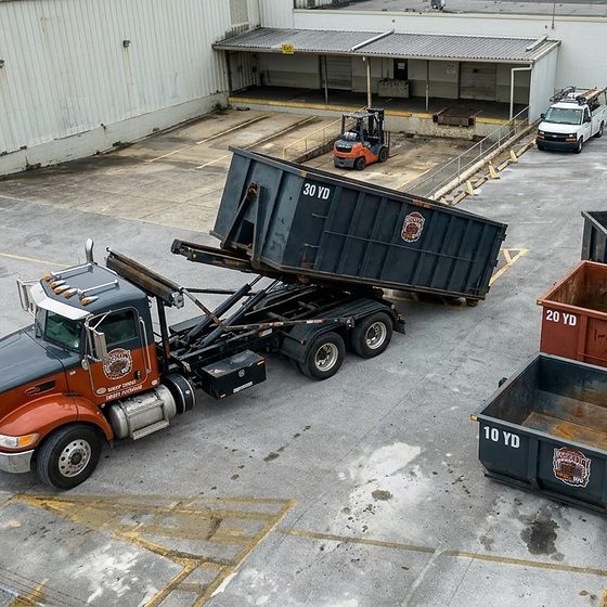 A BrickCity Roll Off truck loading a 30-yard roll-off container in the company yard